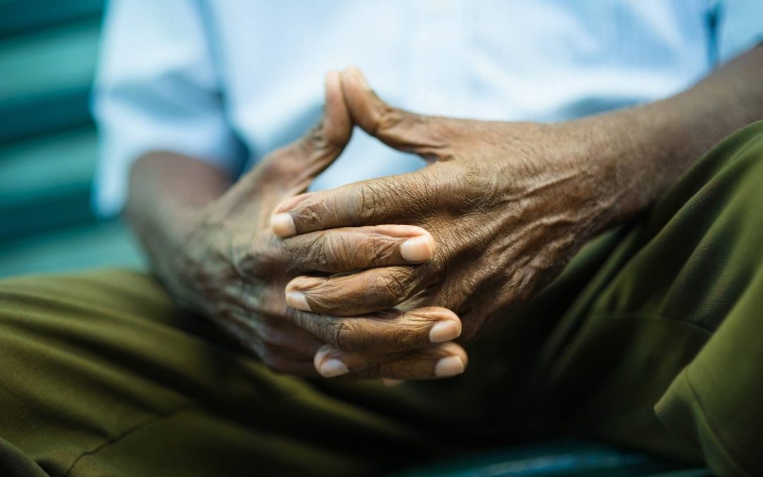 Senior man holds hands clasped