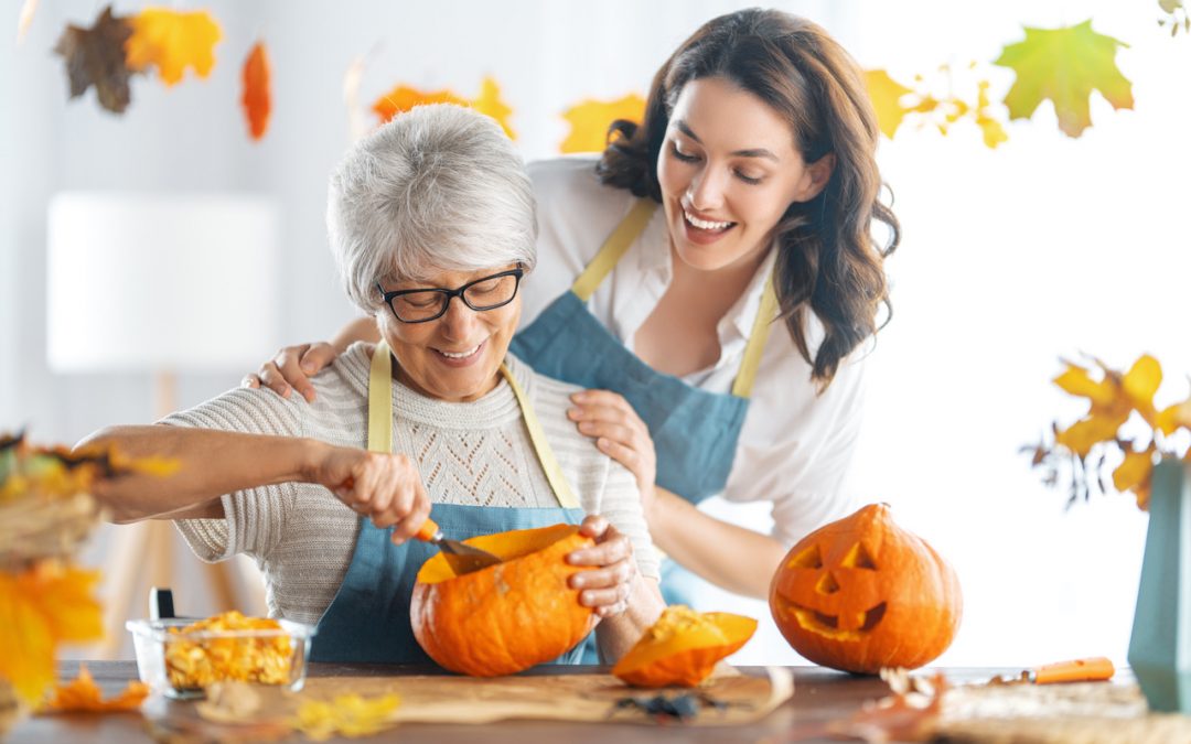 senior woman and cargiver carving pumpkin